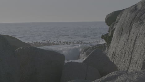 waves hitting the rocks in slowmotion on a sunny day with the sea in the background log