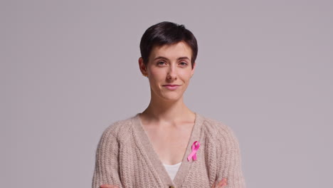 studio portrait of smiling young woman wearing pink breast cancer awareness ribbon against white background 1