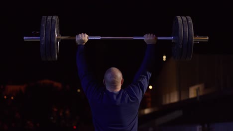 man lifting weights at night