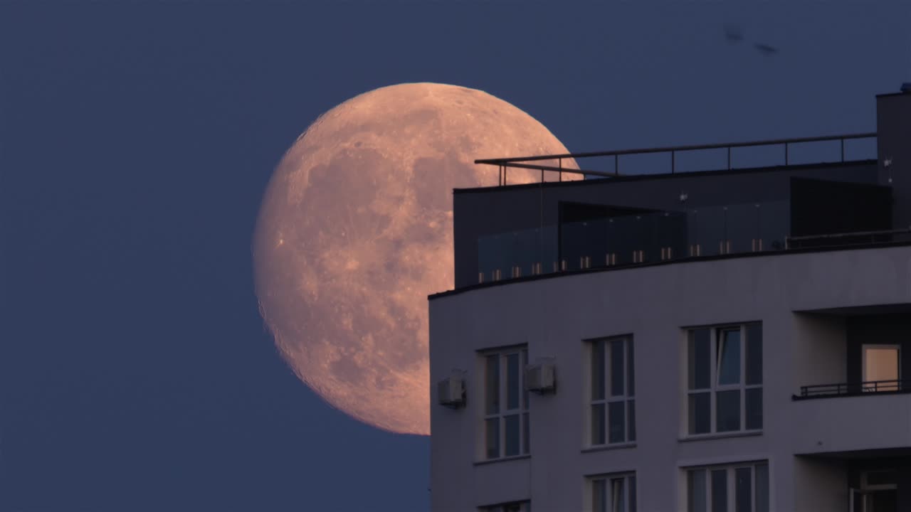뜨는 보름달이 집 지붕을 가로질러 움직입니다.