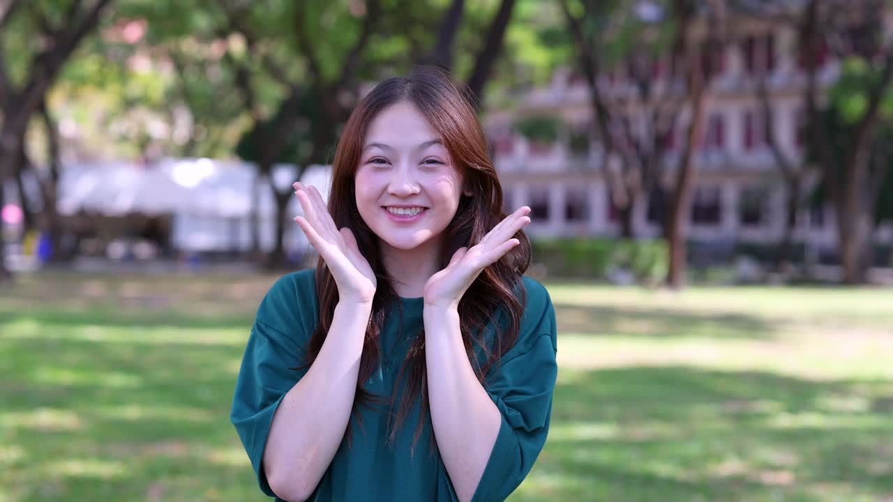 หญิงสาวเอเชียแสดงความประหลาดใจและความสุขในสวนสาธารณะ