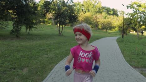 little caucasian runner child girl in pink sportswear running outdoors in park. workout for kids