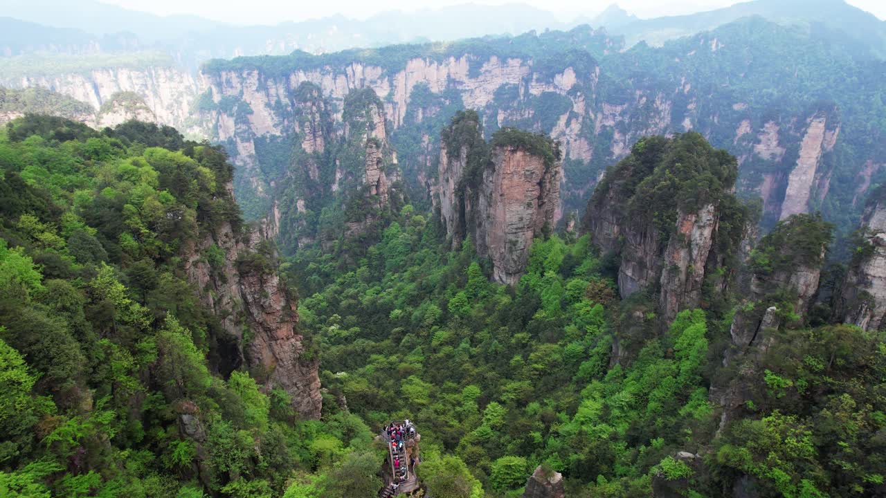 turistas que visitan los mágicos pilares cársticos del parque forestal nacional de zhangjiajie, tilt-up aéreo