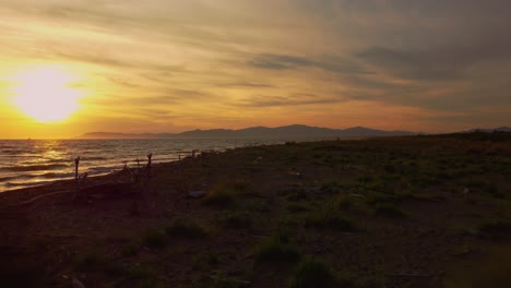 Imágenes-Lentas-Cinematográficas-De-Drones-Aéreos-Bajos-De-La-Puesta-De-Sol-En-Una-Playa-De-Arena-En-La-Costa-Cerca-De-Alberese-En-El-Icónico-Parque-Natural-Maremma-En-Toscana,-Italia,-Con-Olas,-Islas-Y-Un-Espectacular-Cielo-Rojo