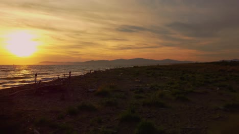 imágenes lentas cinematográficas de drones aéreos bajos de la puesta de sol en una playa de arena en la costa cerca de alberese en el icónico parque natural maremma en toscana, italia, con olas, islas y un espectacular cielo rojo