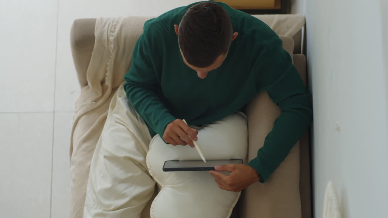 Freelance UX Designer Using Pencil and Tablet PC on Sofa