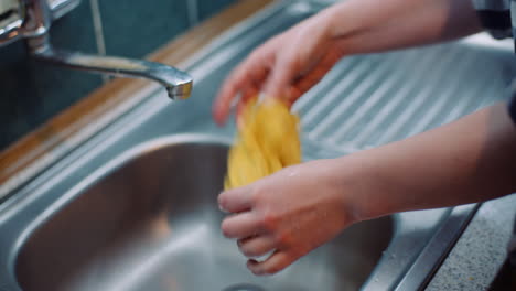 mujer desperdicia agua enjuagando trapo en el fregadero
