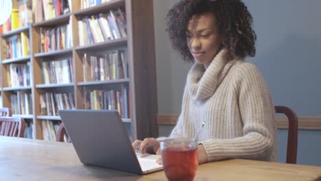 mujer estudiante casual sentada en una cafetería y usando una computadora portátil