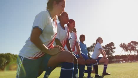 Female-soccer-players-stretching-their-legs-on-soccer-field.-4k