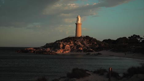 Rottnest-lighthouse-capturing-the-last-of-the-sun-at-sunset,-moody,-slomo