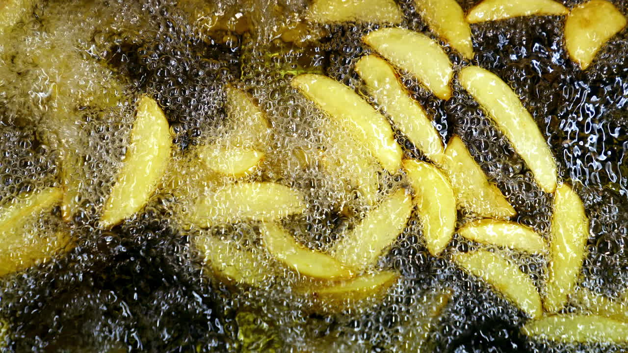 Golden potato in hot oil. French fries in the deep fryer are fried. Cooking crispy fries. Close-up.