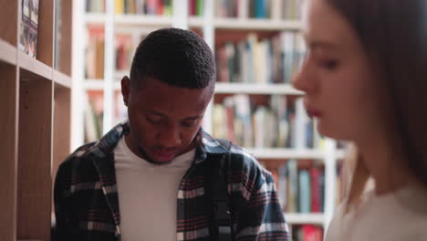 estudiantes universitarios escanean libros de pie entre estanterías. joven con compañera aprende libro preparándose para la escritura de proyectos de ciencia. visitantes de la biblioteca