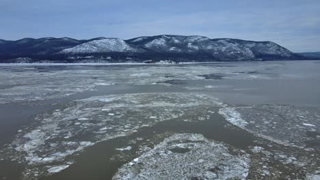 Aerial-drone-footage-of-an-icy-river-and-snow-covered-mountains-during-winter-in-America-in-the-Appalachian-mountain-range,-after-fresh-snowfall