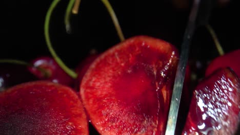 cuchillo afilado y brillante cortando cerezas por la mitad