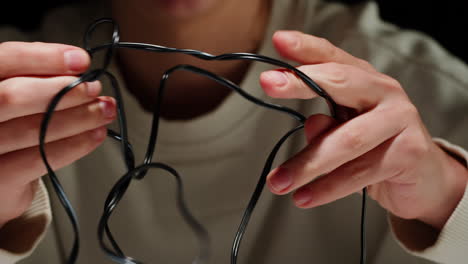 young woman trying to untangle the black headphones close-up. tangled wires on table. trying to untangle many messy cables