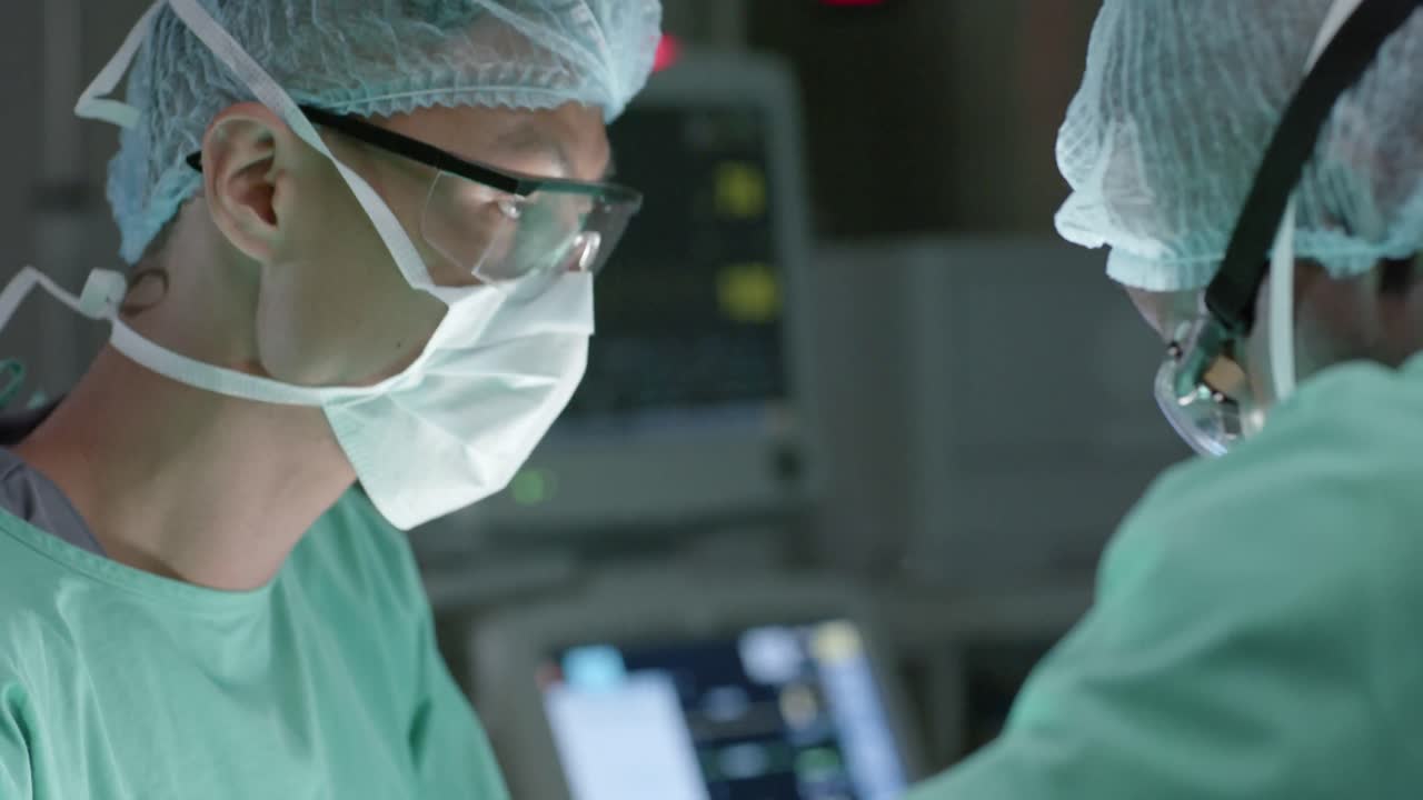 Diverse surgeons with face masks during surgery in operating room in slow motion