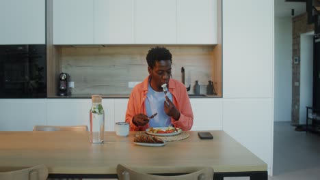 hombre comiendo una comida en una cocina moderna