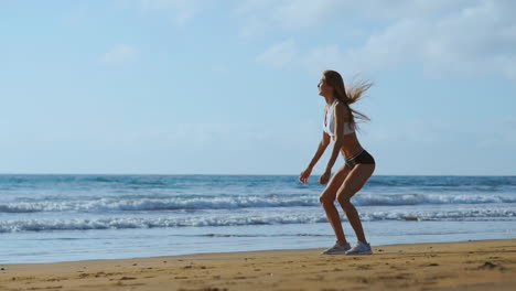 fitness young woman working out core and glutes with bodyweight workout doing squat exercises on beach. sporty girl squatting legs as part of an active and fit life. stedicam shoot