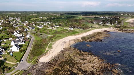 Coastal-village-with-beach-and-houses-under-clear-sky,-aerial-view