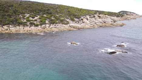 drone aerial moving forward and pan down over beautiful blue water and white rocks on a sunny day in wilsons promontory