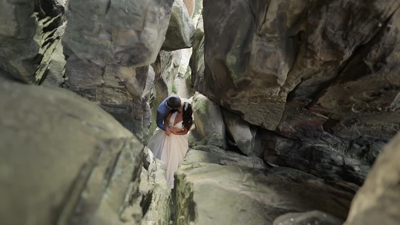 el novio con la novia de pie en la cueva de las colinas de la montaña.