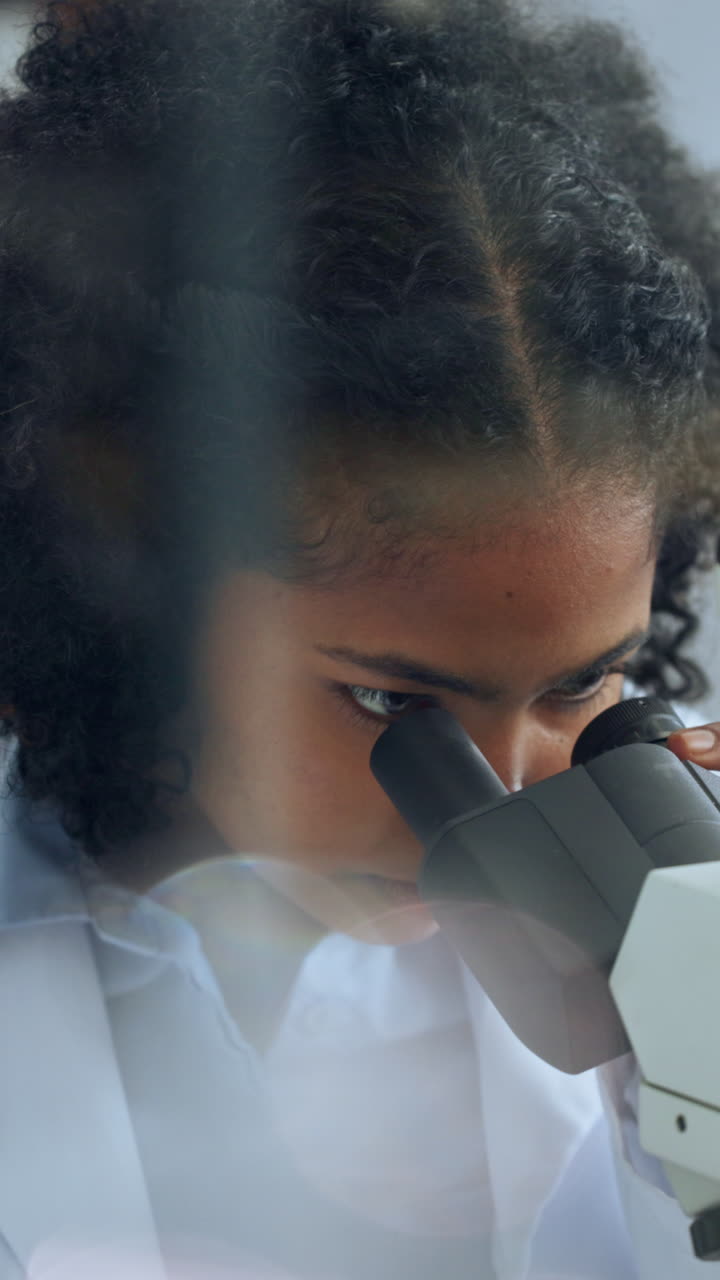 Giovane scienziata che osserva al microscopio in un laboratorio