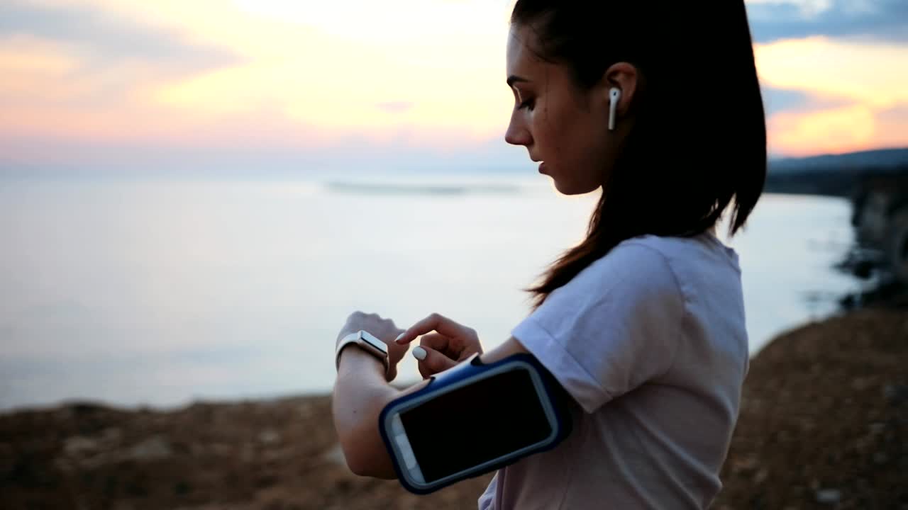 mujer activa comprobando el reloj inteligente durante el descanso de correr en la naturaleza