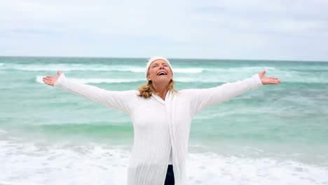 mujer jubilada extendiendo sus brazos por el mar