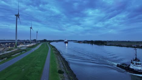 small riverboat followed not far behind by large container ship, aerial