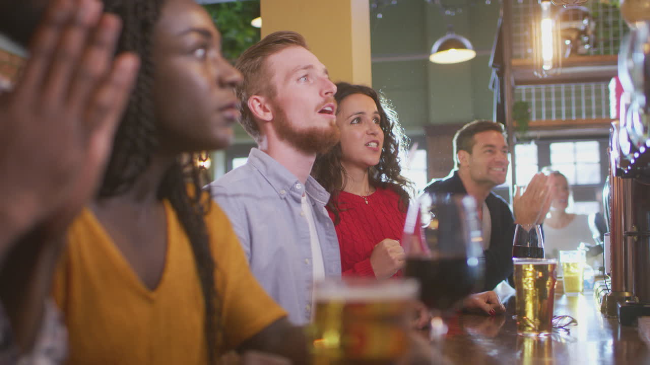 Gruppo di clienti delusi in un bar sportivo che guardano un evento sportivo in televisione mentre la squadra perde