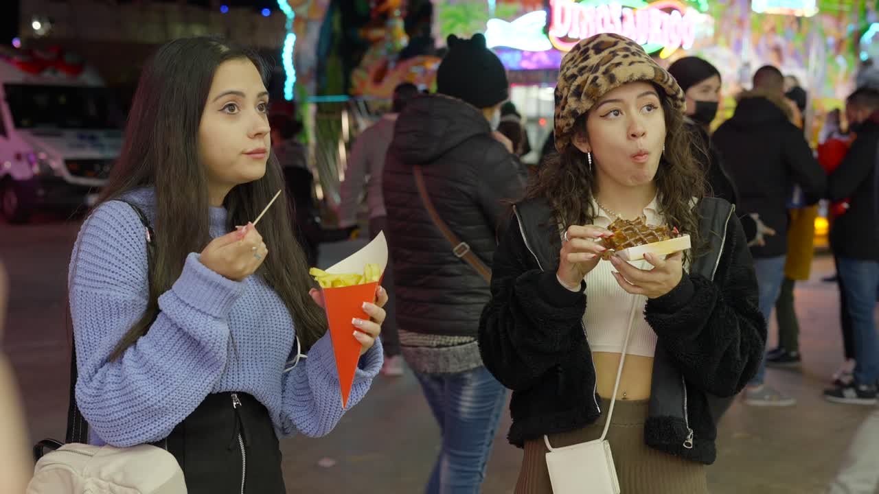 Two girls enjoying street food at a winter fair
