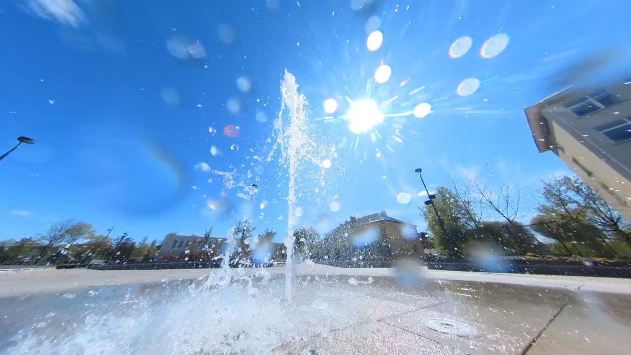 Fountain Water Falling On The Camera Lens On A Sunny Day