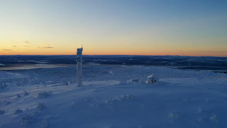 aerial view orbiting snow covered lapland remote cabin and communications tower overlooking polar wilderness at sunrise