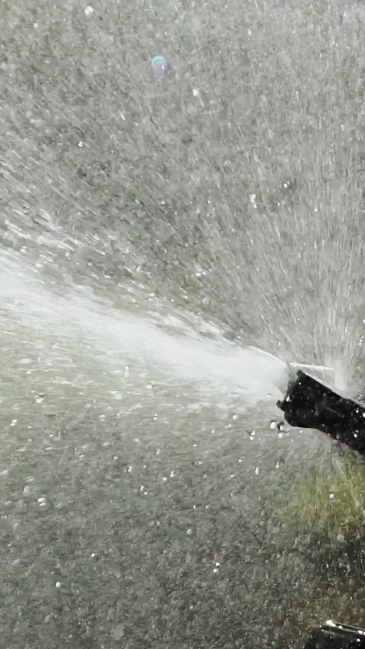 drops of water are watering plants in the yard. Automatic watering system of plants. Aerosol irrigation of garden. Slow motion Vertical video