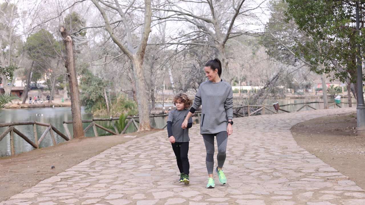 공원 에서 보행로 를  ⁇ 고 있는 아들 과 함께 미소 짓고 있는 스포츠 여자