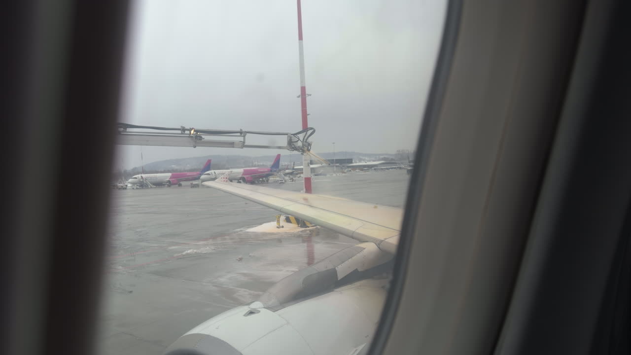 Ripresa al rallentatore filmata dall'interno di un aereo della procedura di sbrinamento delle ali durante l'inverno con liquido spruzzato sulla parte superiore delle ali