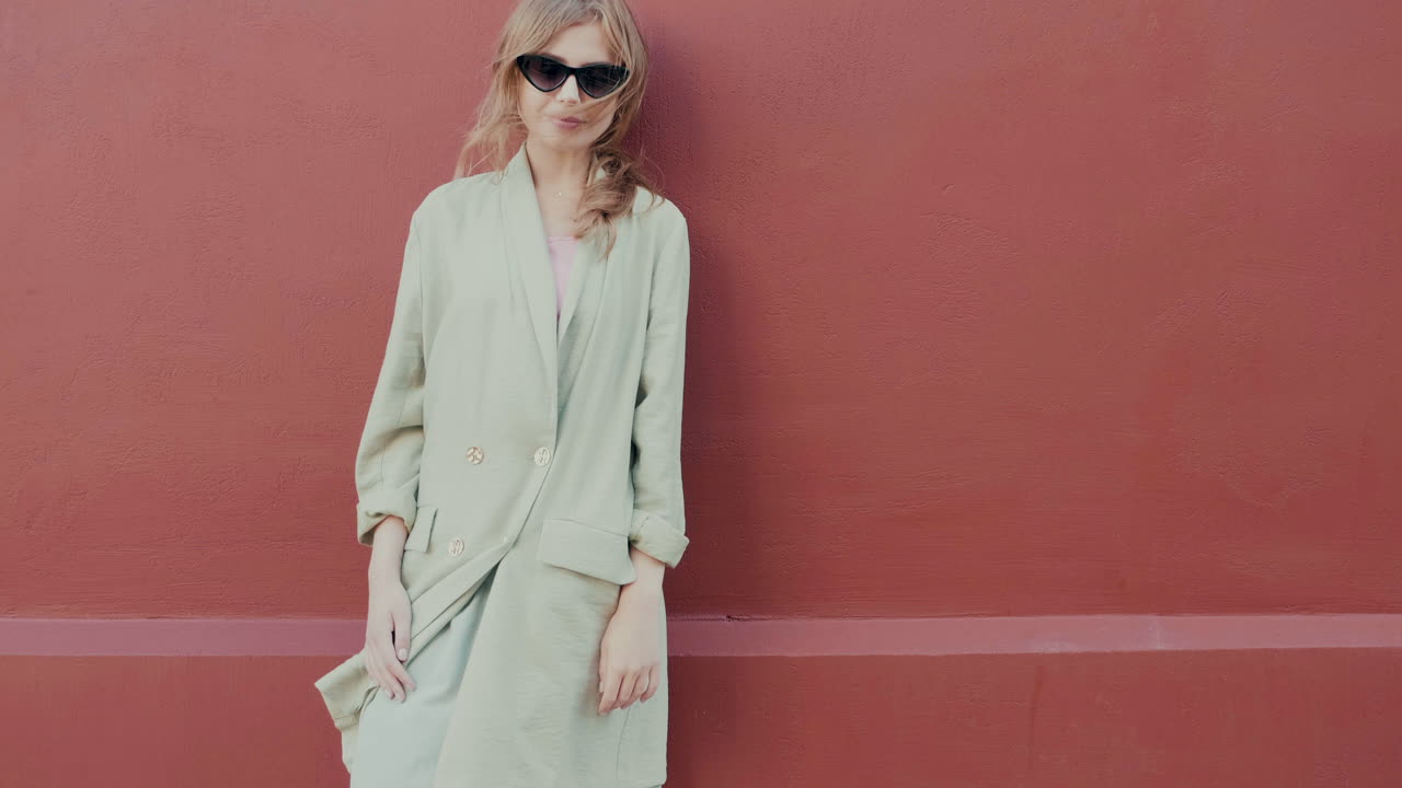 은 벽 앞에 포즈를 취하는 세련된 여성