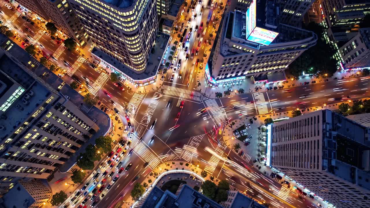 Aerial view of a bustling city intersection at night, showcasing vibrant light trails