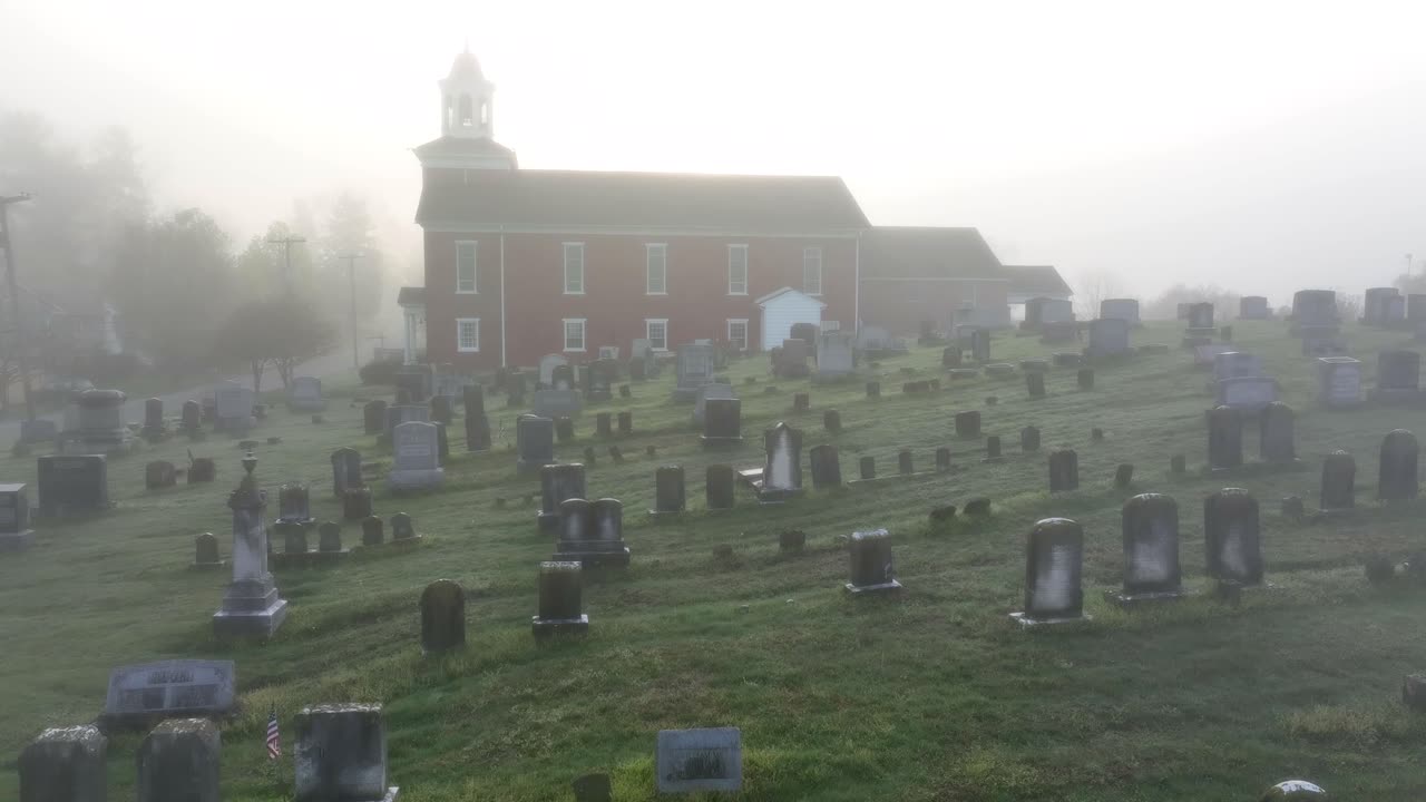 una espeluznante niebla envuelve el viejo cementerio frente a la iglesia roja en el establecimiento de tiro