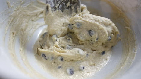 mixing chocolate chip cookie dough cake mixture in a bowl with a wooden spoon