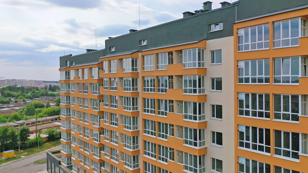 Construction of a modern building in the city. Facade of multistory apartment house with plastic windows in the city. Building of a new architecture concept