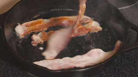 cast iron pan on stove frying bacon
