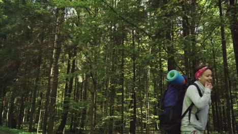 turistas divertidos caminan a lo largo de la carretera cerca del bosque comparando el camino con el mapa