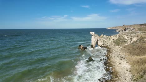 Waves-crash-against-the-rocky-shoreline,-showcasing-Crimea's-natural-beauty-under-a-clear-blue-sky