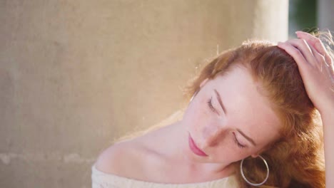 el viento que sopla el pelo rojo y rizado, la luz del sol cega a la hermosa joven natural con un vestido ligero