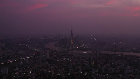 Vista-Aérea-De-La-Ciudad-De-Ho-Chi-Minh-Y-El-Río-Saigón-En-El-Crepúsculo-Con-Luz-Ambiental-Y-Artificial