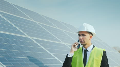 an engineer walks along the solar panels talking on the phone