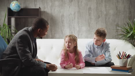 Little girl tells new words to teacher near brother at home