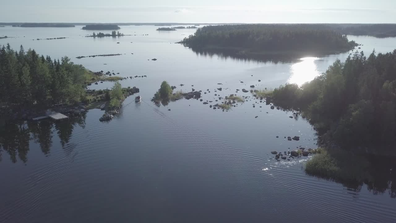 Aerial, descending, drone shot, tilting towards a motorboat, driving between small islands, tranquil sea, in the Kvarken archipelago, on a calm and sunny, summer day, in Finland - Flat color profile