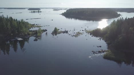 aerial, descending, drone shot, tilting towards a motorboat, driving between small islands, tranquil sea, in the kvarken archipelago, on a calm and sunny, summer day, in finland - flat color profile